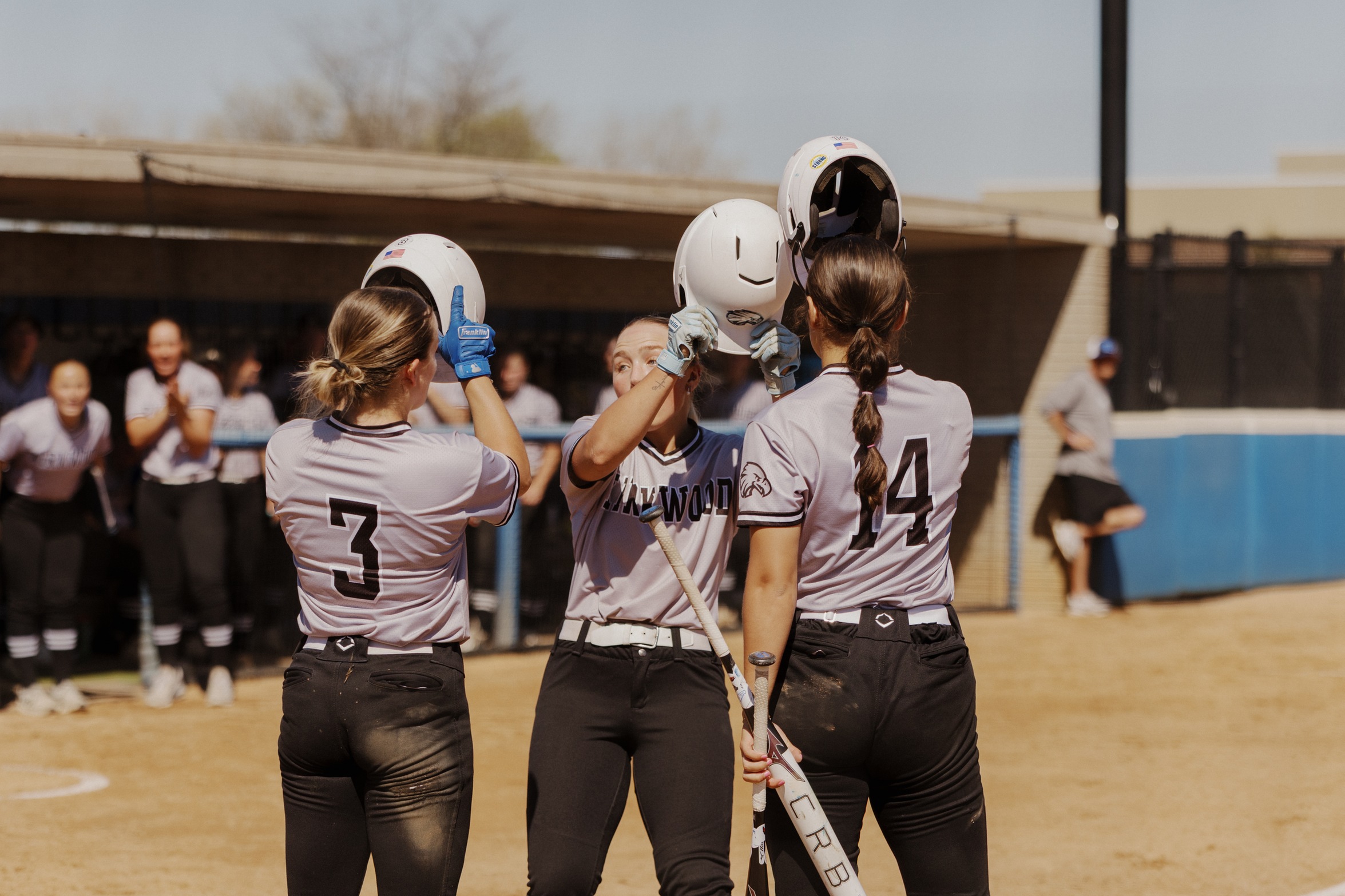 Kirkwood Softball players touching helmets at home plate.